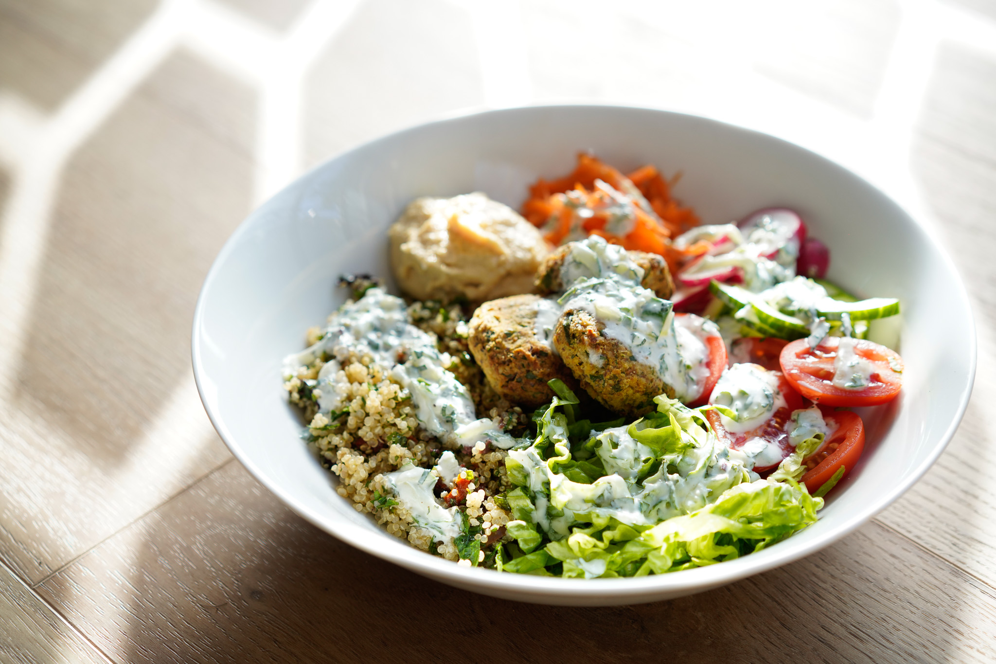 Brightly coloured bowl of vegetables, grains, protein and topping.