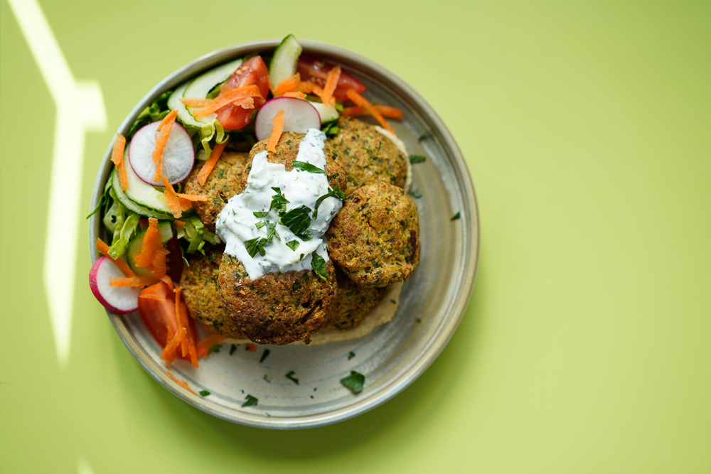 Colourful plate of homemade falafels and salad on a lime green table.